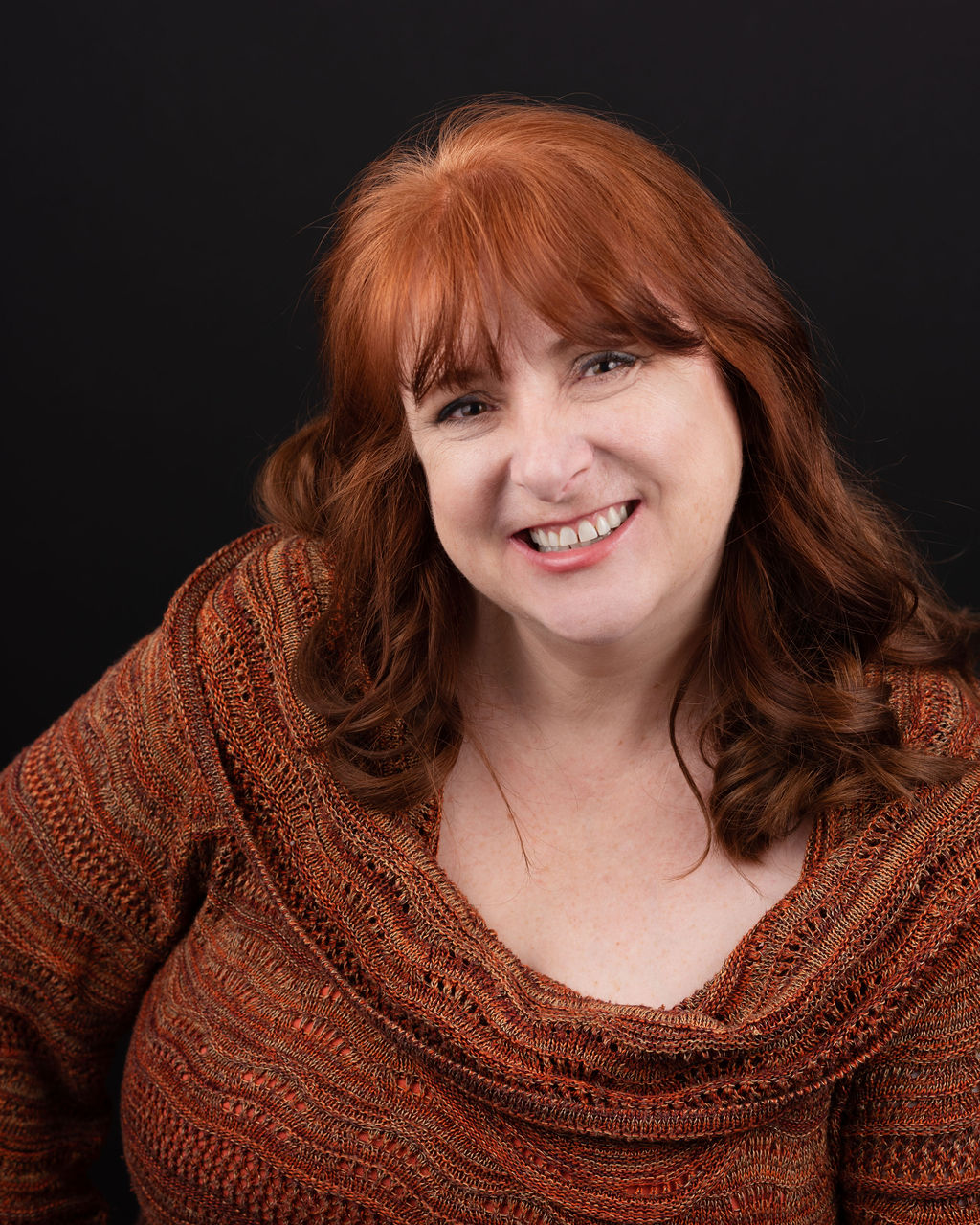 Headshot of Kristal Seid, a musical theatre coach, wearing a rust-colored sweater, exemplifying professionalism in the performing arts.